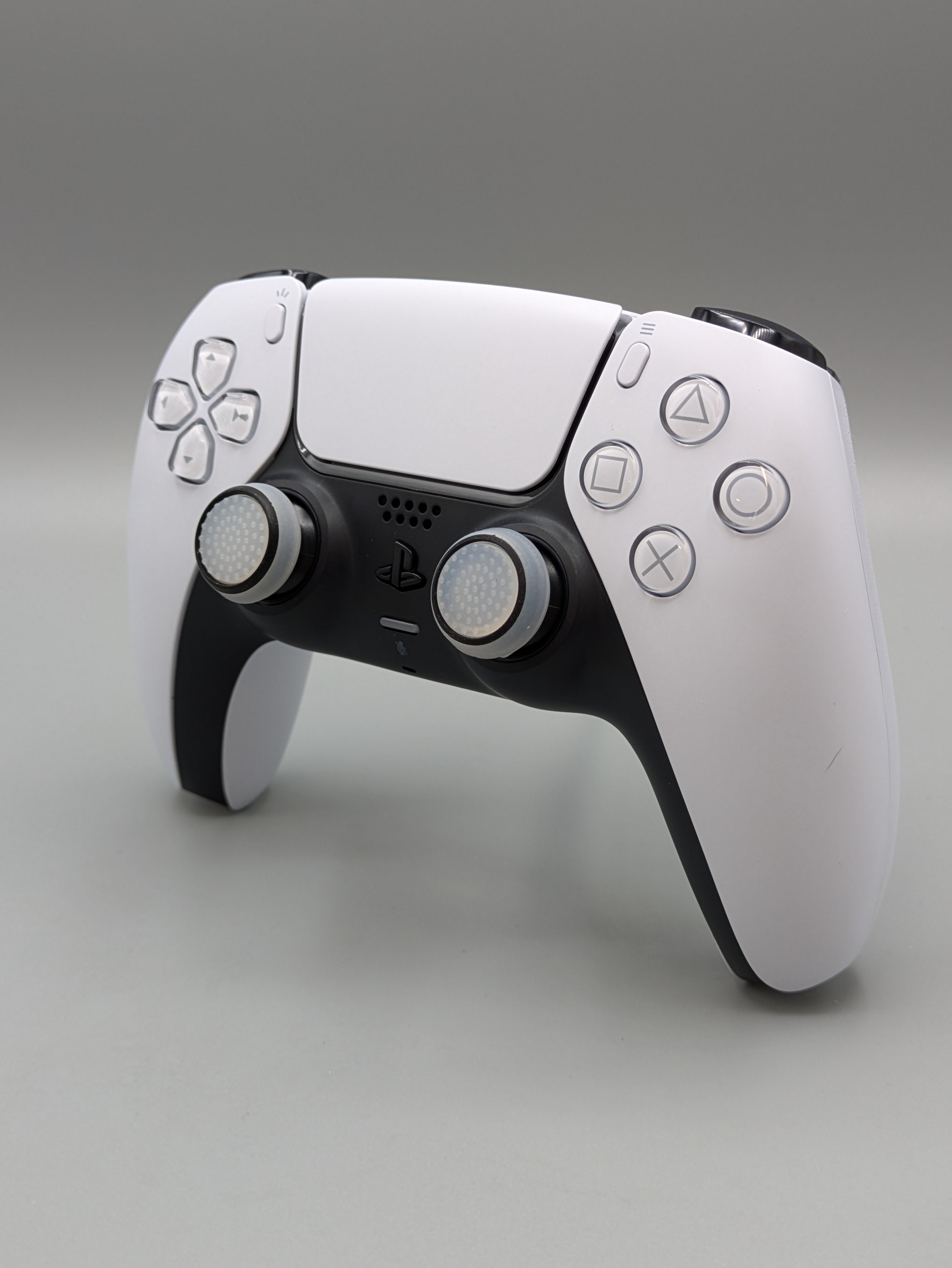 Custom PS5 controller showcasing the GOAT thumbstick toppers in white and black - side view